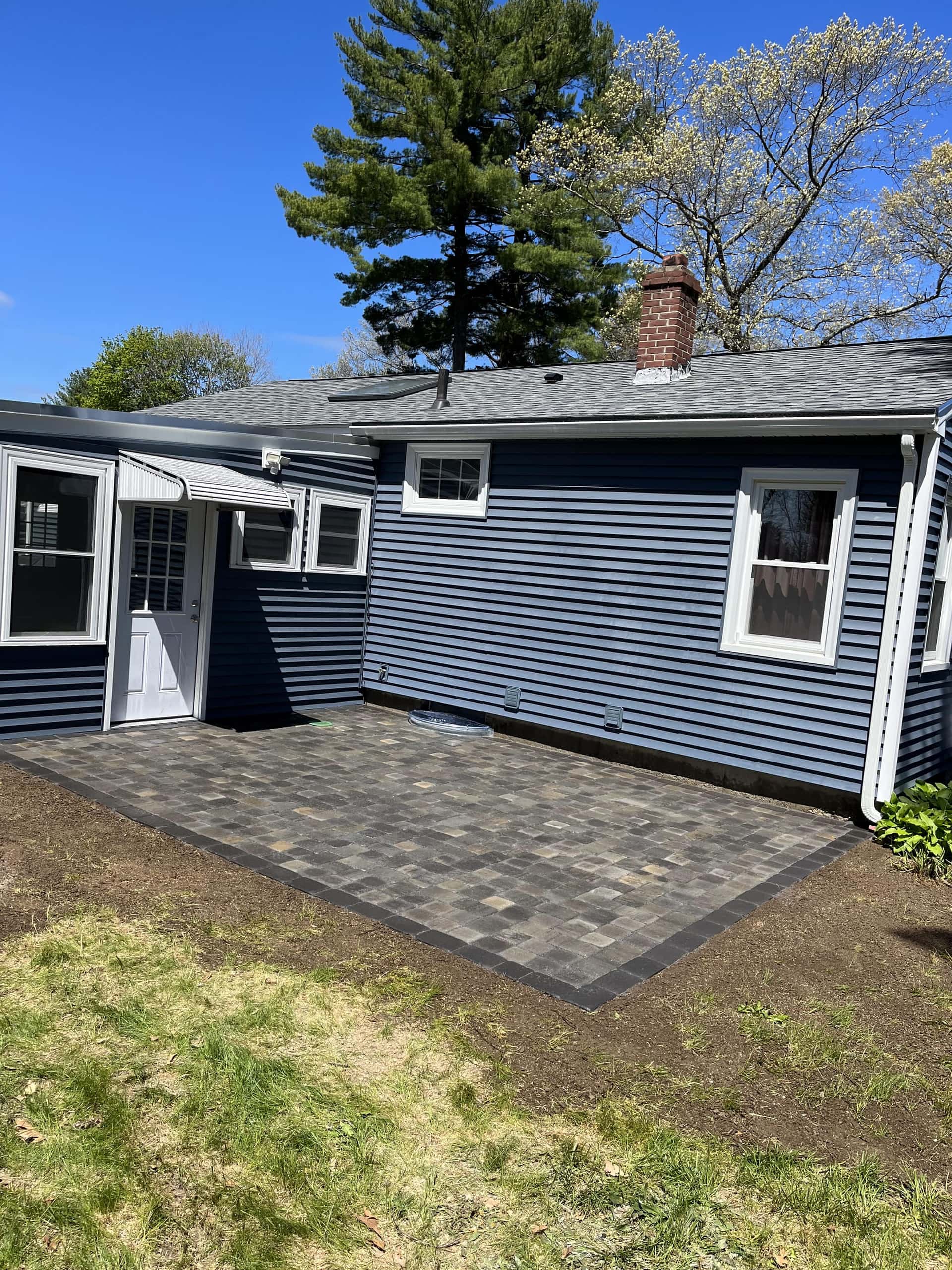 Paver patio installed around a home in Hudson, MA by YellowStone Masonry Group