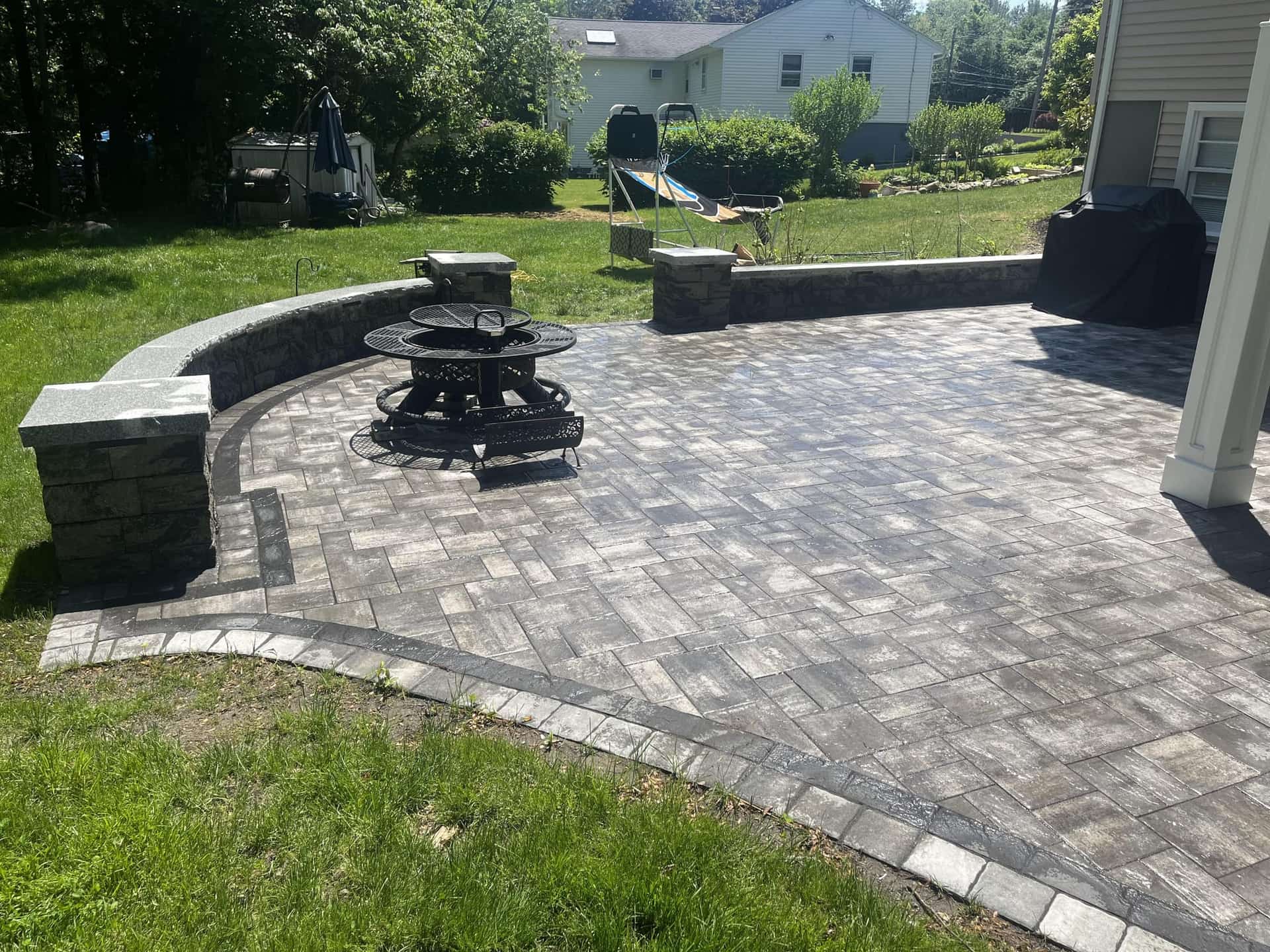 Herringbone paver patio with fire pit and stone seating wall built in Hudson, MA by YellowStone Masonry Group